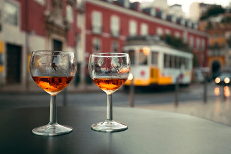 Photo of Two Glasses on a Table with Lisbon Trolley in Background